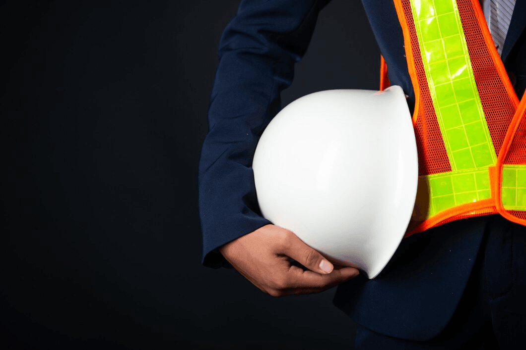 Worker holding a white hard hat wearing a safety vest